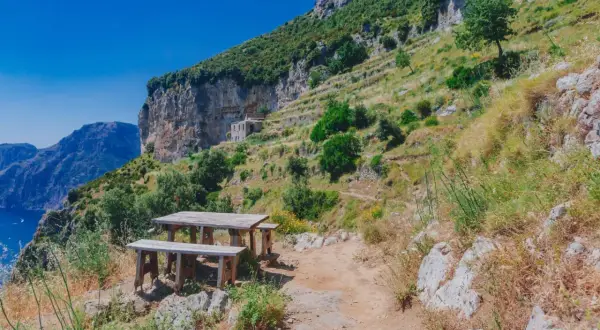 Un tavolo da picnic in legno attende i viaggiatori sul Sentiero degli Dei, con vista mozzafiato sul mare e sulle montagne.