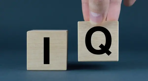 Dłoń układa kostkę z literą "Q" obok kostki z literą "I". Co to jest IQ?