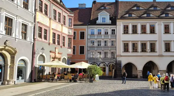 Café mit Außenbestuhlung auf einem historischen Platz mit bunten Häusern.