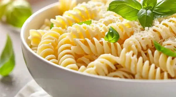 En skål med fusilli-pasta, toppad med riven ost och färsk basilika. Perfekt för ett snabbt pastasås recept.