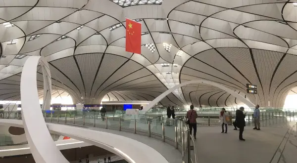 Nowoczesne lotniska w Chinach zachwycają architekturą. Wnętrze terminalu z flagą Chin i futurystycznym dachem.