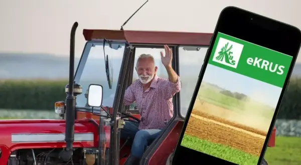Uśmiechnięty rolnik w traktorze macha do kamery, obok smartfon z aplikacją eKRUS, która ułatwia zarządzanie prawem do emerytury rolniczej według nowych zasad.