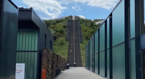 Der **Metabolon** in Lindlar, ein Ort für Forschung und Lehre der TH Köln, mit einer langen Treppe, die zu einem Hügel führt.