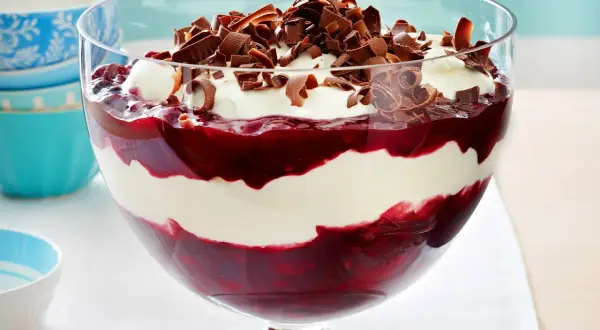 Schichtdessert mit Kirschen und einer luftigen Creme aus Mascarpone, garniert mit Schokoladenlocken.