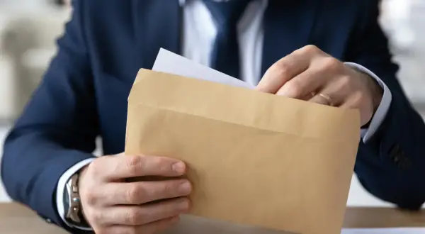 Mężczyzna w garniturze wkłada dokument do brązowej koperty. Czy odpowiedź na apelację doręcza się bezpośrednio pełnomocnikowi?