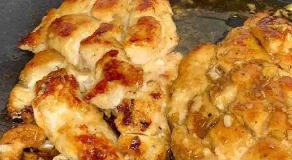 Succulento pollo in padella, dorato e saporito, con pezzetti di aglio che aggiungono un tocco in più.