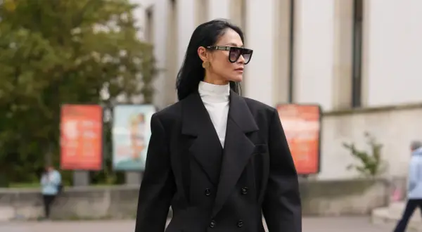 Stilvolles Outfit: Schwarzer Blazer über einem weißen Hemd mit Rollkragen kombinieren. Modische Sonnenbrille und goldene Ohrringe runden den Look ab.