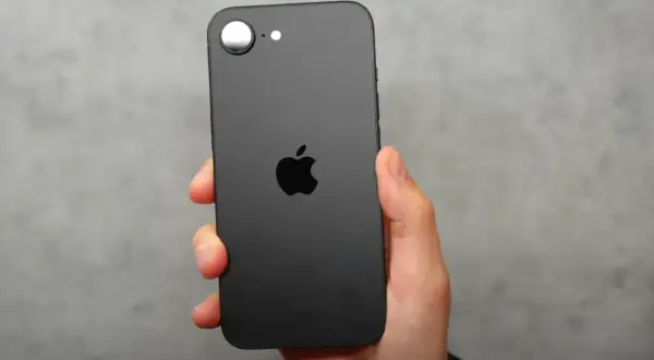 Czarna obudowa iPhone SE 4 z charakterystycznym jabłkiem Apple. Telefon trzymany w dłoni na szarym tle.