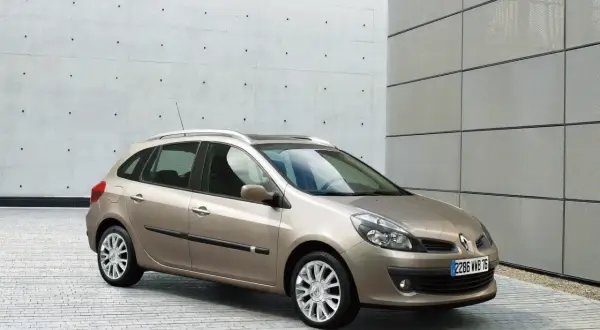 Beżowe Renault Clio 3 1.2 benzyna na tle nowoczesnej architektury.