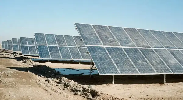 Fila de placas solares sucias bajo un cielo azul claro. La suciedad y el polvo cubren la superficie de los paneles, reduciendo su eficiencia.