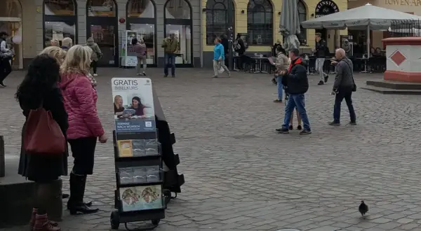Zeugen Jehovas bieten einen kostenlosen Bibelkurs an. Menschen gehen vorbei, einige halten Broschüren in der Hand.