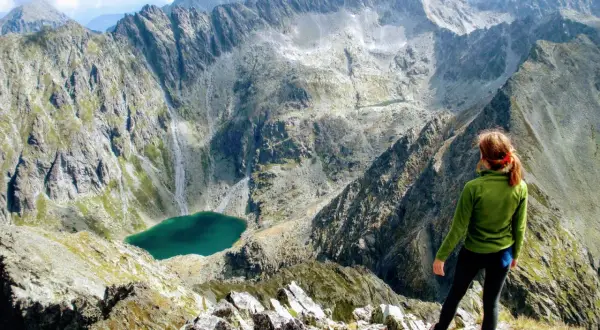 Kobieta podziwia widok na tatrzańskie szczyty i jezioro po pokonaniu szlaku na Krywań.