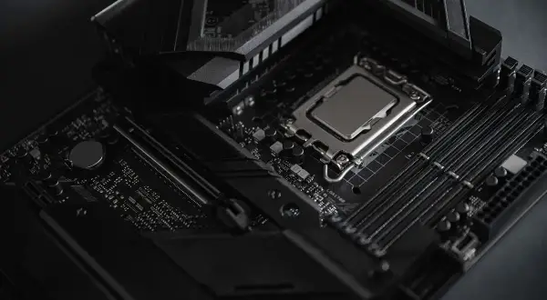 Czarna płyta główna z procesorem i slotami RAM. Widoczny radiator i elementy chipsetu.