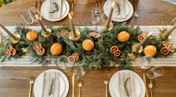 Vackert dukat julbord med granris, apelsiner med nejlikor, torkade apelsinskivor och ljus. En perfekt inspiration för att dekorera julbordet.