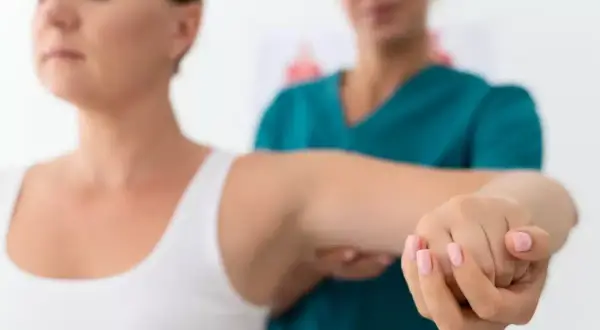 Fizjoterapeuta pomaga pacjentce z zespołem skrzyżowania dolnego w ćwiczeniach ramienia.