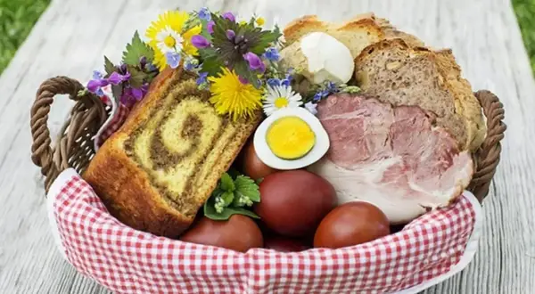 Co się daje do koszyczka wielkanocnego? Widać tu babkę, jajka, chleb, wędlinę i kwiaty.