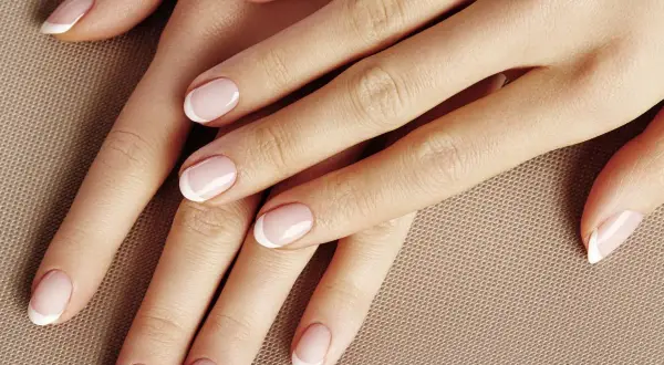Dłonie z perfekcyjnym manicurem french kombinowany. Delikatny róż i biel podkreślają elegancję.