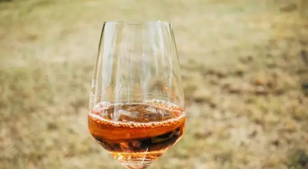 Un bicchiere di passito di Pantelleria, con il suo colore ambrato e le bollicine che danzano, pronto per essere gustato all'aperto.