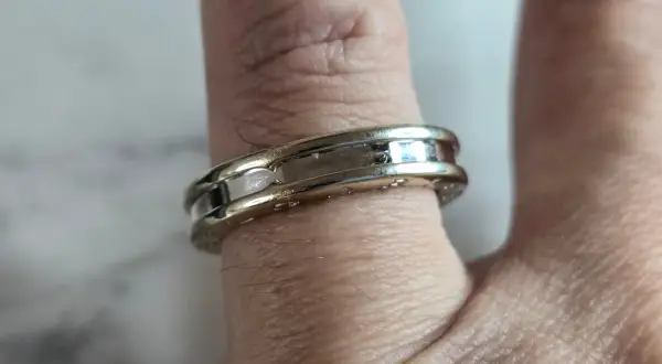 Anillo Bulgari de oro blanco y detalles pulidos, adornando un dedo con su diseño elegante y atemporal.