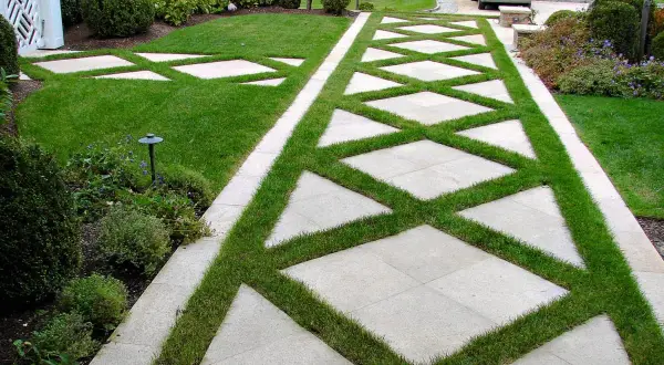 Nowoczesny podjazd z płyt i trawy, co zamiast kostki na podjazd. Wzór w romby z zielenią.