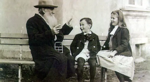 Lew Tołstoj w otoczeniu swoich dzieci, siedząc na ławce, opowiada im zapewne jakąś historię.