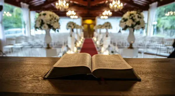 Otwarta Biblia na drewnianym stole, w tle udekorowana sala weselna. Symbolika 666 znaczenie w kontekście duchowym.