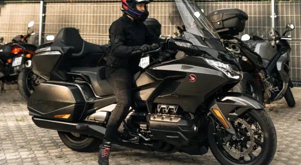Kobieta w kasku na potężnym motocyklu turystycznym, obok inne rodzaje motocykli.