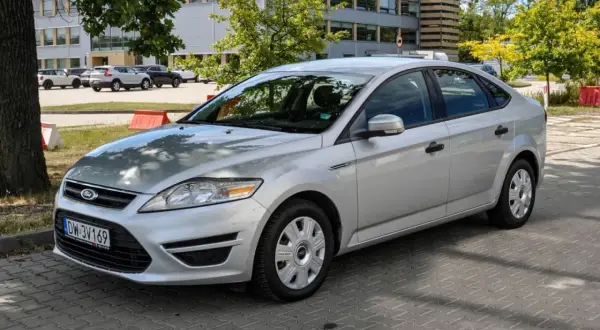 Srebrny Ford Mondeo MK4 2.0 TDCI zaparkowany na kostce brukowej przed budynkiem.