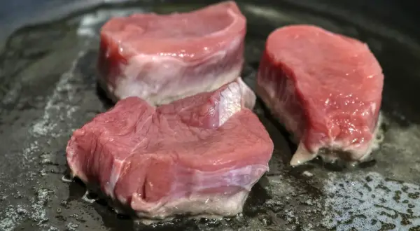 Drei saftige Schweinefilet-Medaillons braten in einer heißen Pfanne. Perfekt für köstliche Schweinefilet Rezepte.
