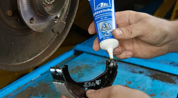 Mechanik aplikuje smar ATE Plastilube na prowadnice szczęki hamulcowej, dbając o prawidłowe działanie układu hamulcowego.
