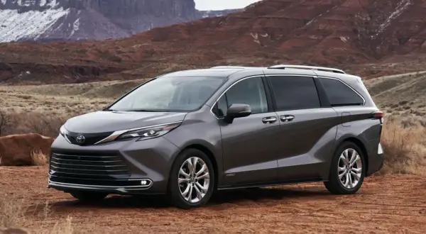 Szara Toyota Sienna na tle pustynnego krajobrazu z czerwonymi skałami.