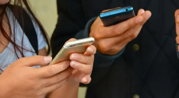 Dwie osoby trzymają telefony. Zastanawiasz się, jak sprawdzić, gdzie ostatnio logował się telefon?