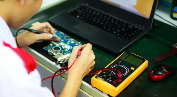 Technik elektronik bada płytę główną laptopa multimetrem. Zastanawiasz się, ile zarabia technik elektronik?