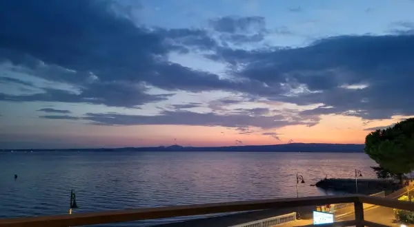 Zachód słońca nad morzem w Gaeta. Niebo w odcieniach błękitu i różu, spokojna woda, widok z tarasu.