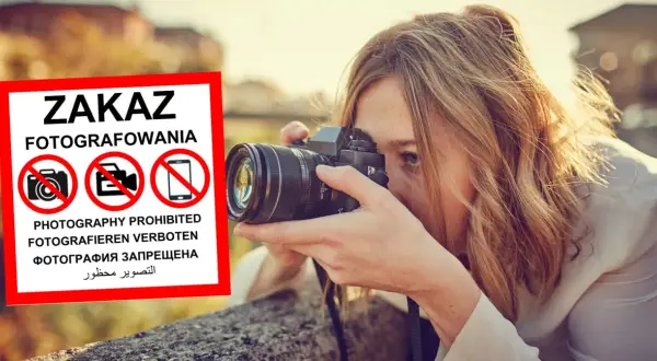 Kobieta z aparatem ignoruje znak zakaz fotografowania.