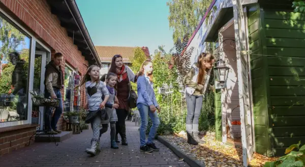 Familie erkundet die Templin Altstadt, vorbei an einem roten Backsteinhaus und einem grünen Schuppen mit Laterne.