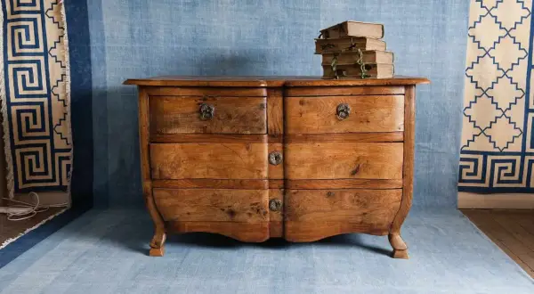 Cajonera de madera rústica, lista para restaurar muebles vintage. Apilado de libros antiguos sobre ella.