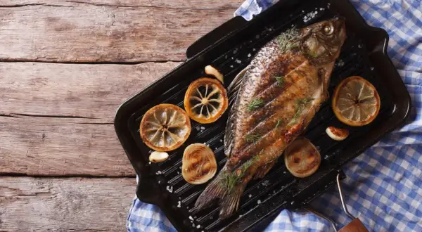 Gegrillter Karpfen mit Zitrone und Rosmarin auf einer Grillpfanne. Ein köstliches Beispiel für Karpfen Gerichte.
