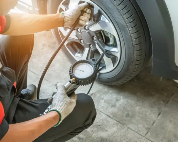 Controllo pressione gomme: il manometro indica pressione gomme troppo alta. Un meccanico con guanti sta verificando la pressione di un pneumatico.