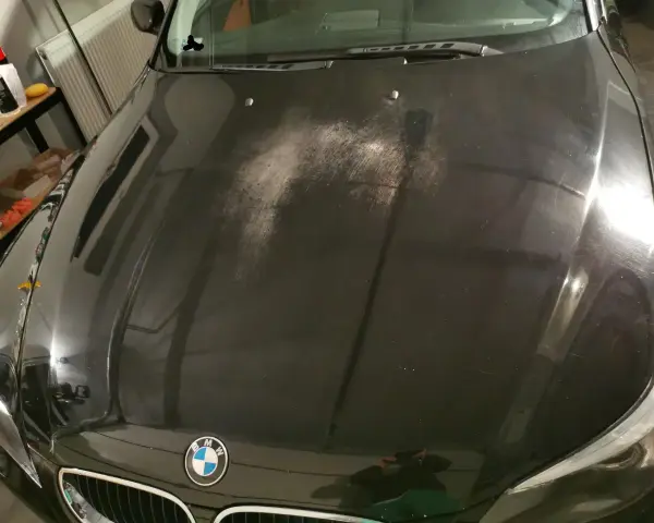 Na czarnej masce BMW widać liczne drobne rysy i zmatowienia, tworzące efekt "oczek na lakierze".