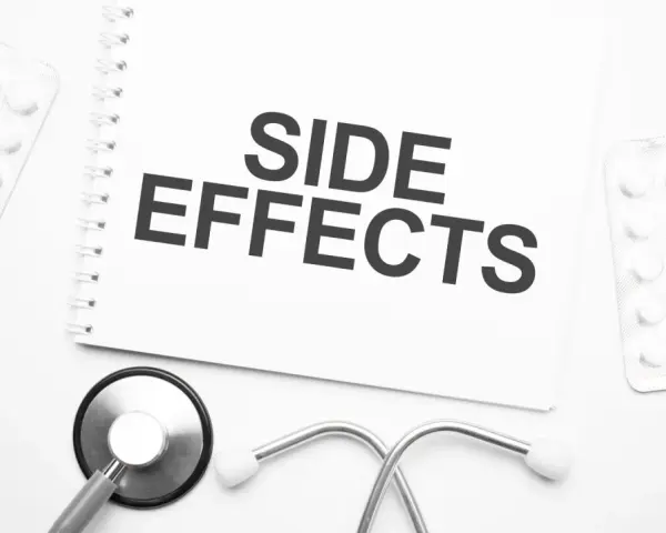 Notatka z napisem "SIDE EFFECTS" obok stetoskopu i opakowań leków. Czy NAC suplement ma skutki uboczne?