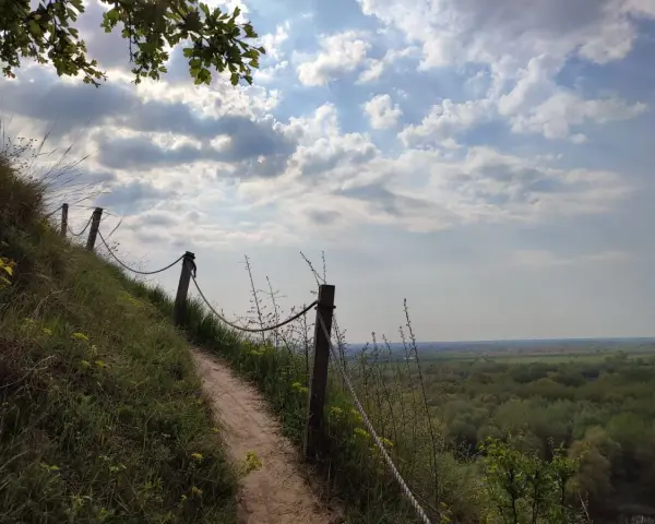 Ścieżka na zboczu Góry Pieprzowe. W oddali rozciąga się zielona dolina.