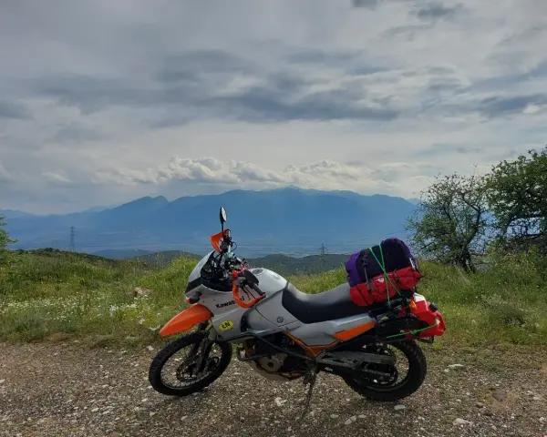 Motocykl gotowy na przygodę, z bagażami na wyprawę. Piękna grecja trasa z widokiem na góry.
