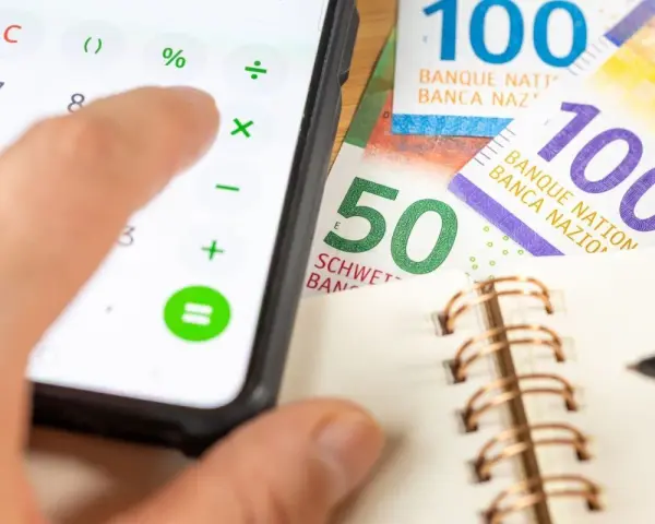 Rechnung für das Kostgeld der Kinder: Ein Handy mit Taschenrechner, Schweizer Franken und ein Notizbuch.