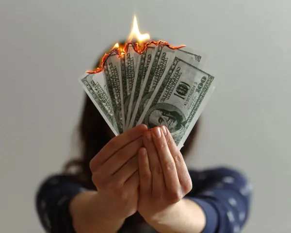 Hands hold burning US dollar bills, a visual metaphor for a use it or lose it budget.