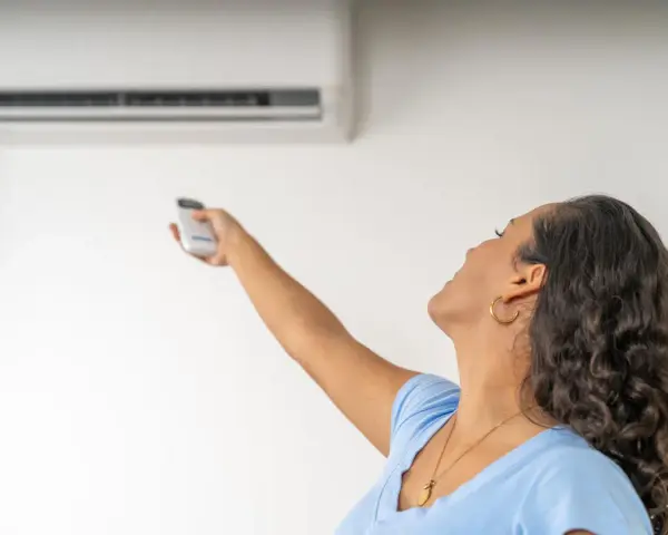 Donna con telecomando regola il condizionatore, la canalina condizionatore design si integra perfettamente.