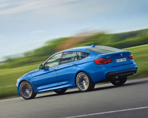 Niebieskie BMW 3 GT w ruchu, ukazujące jego sportowy profil. Warto rozważyć jego wady i zalety przed zakupem.