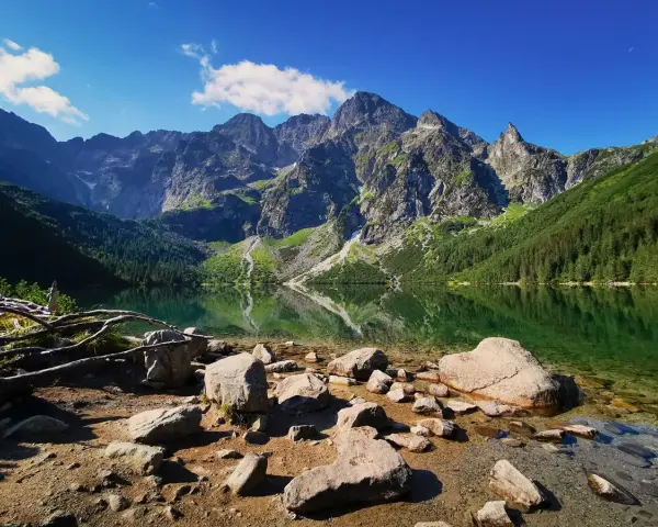 Kamienista plaża nad Morskim Okiem. W tle majestatyczne szczyty Tatrzańskiego Parku Narodowego odbijają się w krystalicznie czystej wodzie.