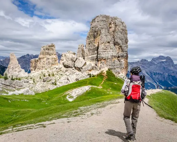 Wanderer auf einer **Cinque Torri Wanderung** mit Blick auf die markanten Felsformationen und die Dolomiten.