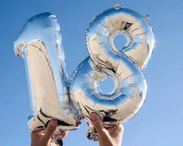 Silberne Folienballons in Form der Zahl 18 vor blauem Himmel.